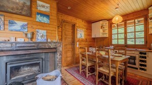 A wooden cabin interior with a fireplace, dining table, chairs, and artwork on the walls. - Chalet Petit Poucet 2BR Retreat in forest, Le Tour (Argentière), France (Le Tour (Argentière))