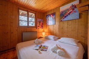 Une pièce de style cabane en bois, avec un lit, une fenêtre et deux tableaux accrochés au mur.