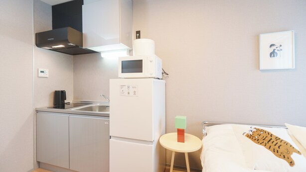 A compact kitchen with a microwave, refrigerator, and a small table. - Tora Hotel Nishikamata (Ota City)