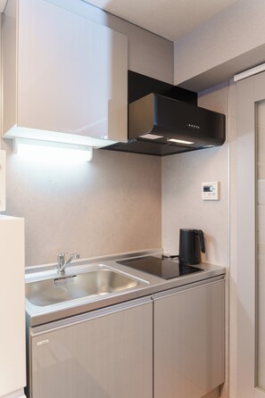 A modern kitchen with stainless steel appliances, a double sink, and a built-in range hood. - Tora Hotel Nishikamata (Ota City)