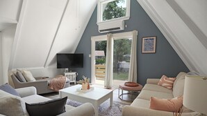 Una sala de estar moderna con techo inclinado, un televisor de pantalla plana en la pared, una mesa de centro blanca y un sofá color beige.
