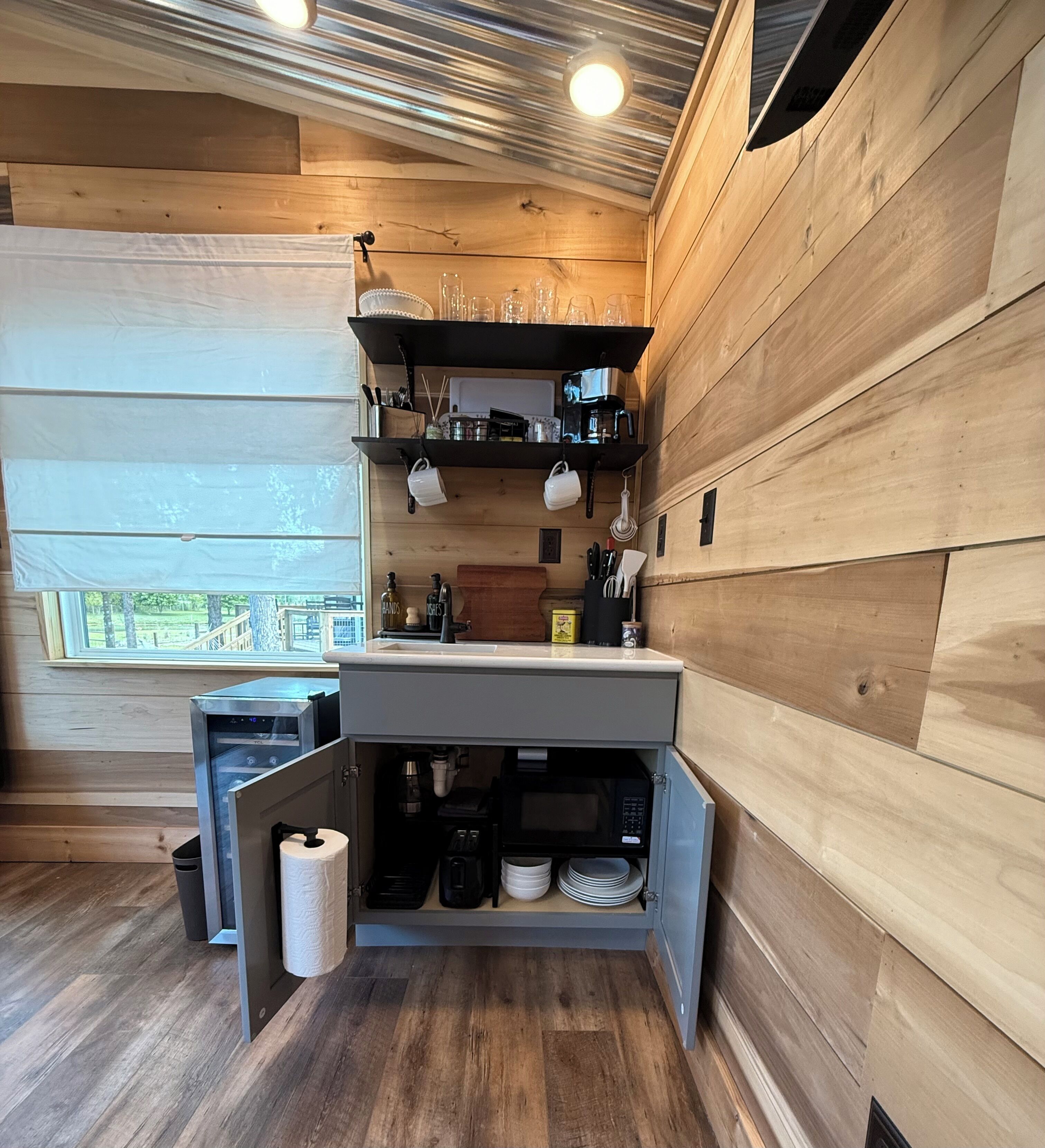 Cocina compacta con paredes de madera, un lavamanos integrado y una ventana con vistas.