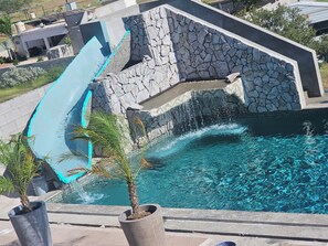 Ein Swimmingpool mit einer Steinmauer und einer blauen Rutsche.