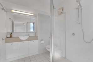 A modern bathroom with a glass shower enclosure, a white sink, and a large mirror. - 1 Jade Court - Centrally Located, Brand New Furnishings (Maroochydore)