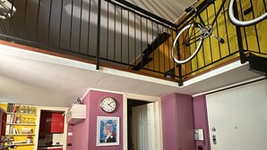 Un vaste espace de vie comprenant un escalier, un vélo, une horloge et une bibliothèque.