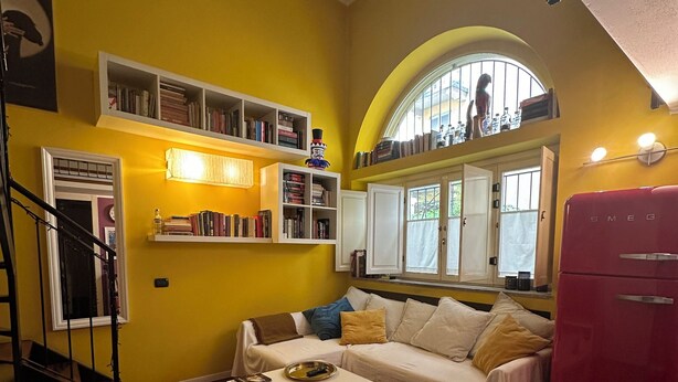 Un salon comprenant un canapé, une table basse, une bibliothèque, un escalier et un réfrigérateur.