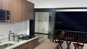 A modern kitchen with a stove, sink, and a view of the city at night. - 2-bedroom apartment, close to the 44th Street area, bus station, airport, and Flamboyant Shopping Mall. (Goiânia)