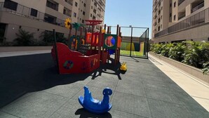 A playground with a slide and climbing structures, surrounded by high-rise buildings. - 2-bedroom apartment, close to the 44th Street area, bus station, airport, and Flamboyant Shopping Mall. (Goiânia)