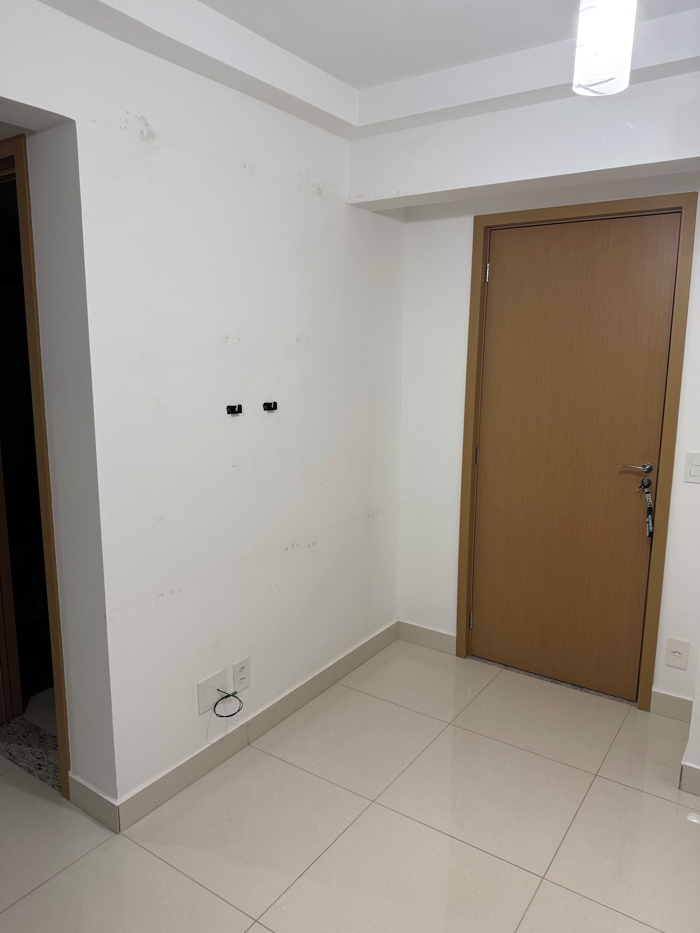A room with a tiled floor, a wooden door, and a light fixture on the ceiling.
