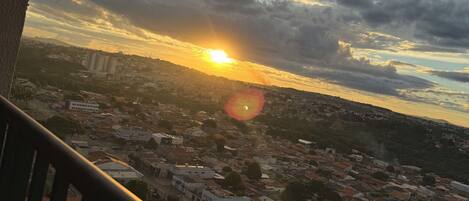 Un paisaje urbano con un atardecer, edificios y una calle bordeada de palmeras.