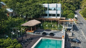 A modern building with a pool, outdoor seating, and a thatched-roof structure. - PhlaidamhillSichon (Sichon)
