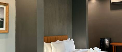 Ein modernes Hotelzimmer mit einem großen Bett, einem Holzkopfende, einem kleinen Tisch und einem Sofa.