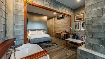 Una habitación de hotel moderna con una cama grande, una zona de estar separada, un escritorio y una bañera.