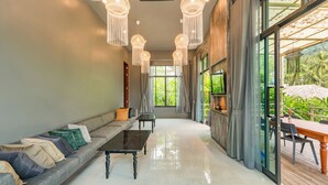 A spacious living area with a sofa, coffee table, and hanging lights. - PhlaidamhillSichon (Sichon)