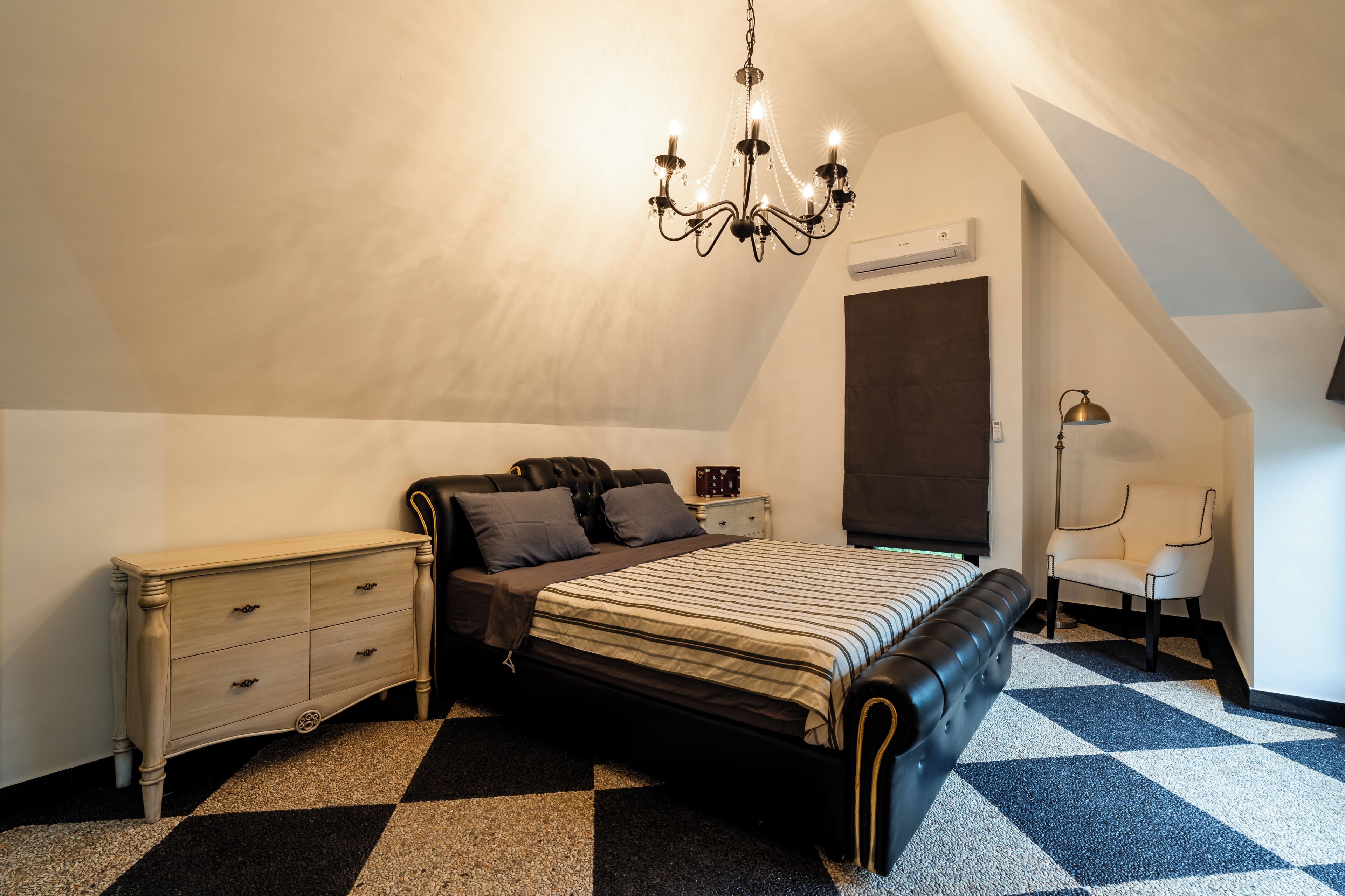 Une chambre à coucher avec un lit, une commode, une chaise et un lustre.