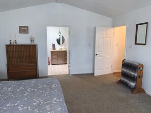 A bedroom with a bed, dresser, and a door leading to a bathroom. - The Country Nook-Rustic Charm & Starry Nights! (Temple)