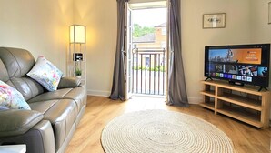 Sala de estar con sofá de cuero, televisor, alfombra tejida y vista a través de una puerta.