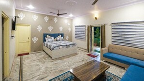 Un dormitorio con cama, sofá, mesa de centro y ventilador de techo.
