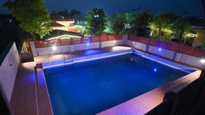 Una piscina nocturna con valla roja e iluminación.