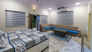 Una habitación con cama, sofá, mesa de centro y ventilador de techo.