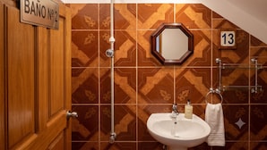 A bathroom with a shower, a sink, a mirror, and a towel rack.