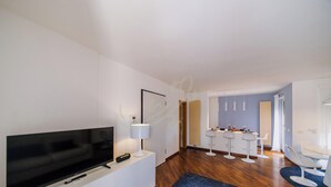 Ein modernes Wohnzimmer mit Fernseher, einer Lampe und einer Fernbedienung auf einer weißen Konsole.