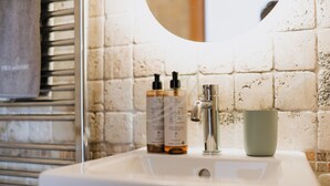 Ein Waschbecken mit Pflegeprodukten, einem Wasserhahn und einer Tasse.