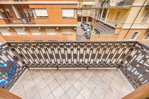 A multi-story building with balconies, a tiled floor, and parked cars. - Eleven Maison [Centro Cuneo zona sferisterio] (Cuneo)