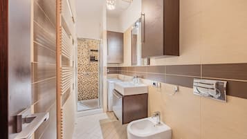 Ein modernes Badezimmer mit Dusche, Waschbecken und Bidet, mit Fliesenboden und Holzelementen.