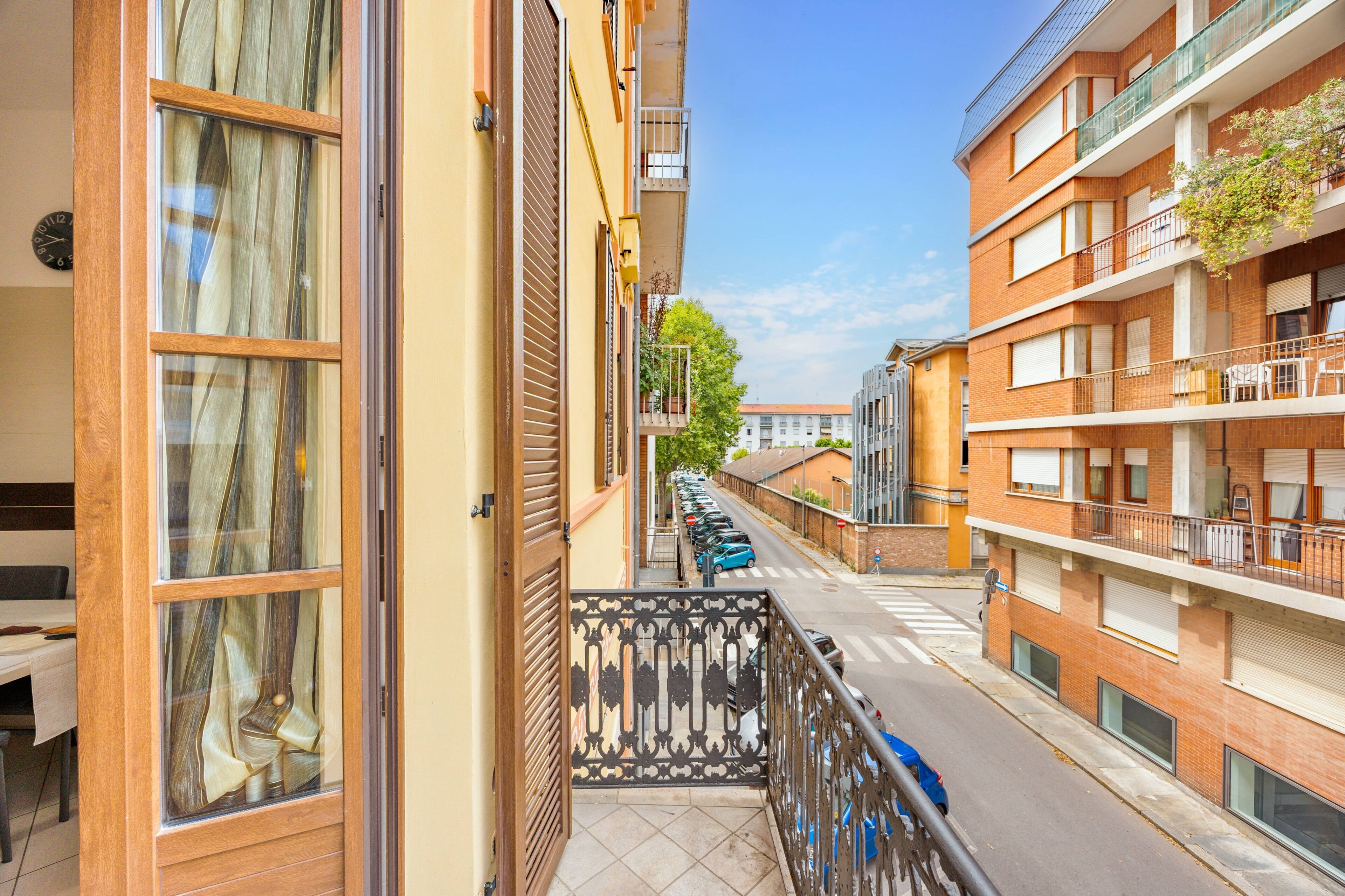 En boligbygning med balkon, udsigt til gaden og parkerede biler.