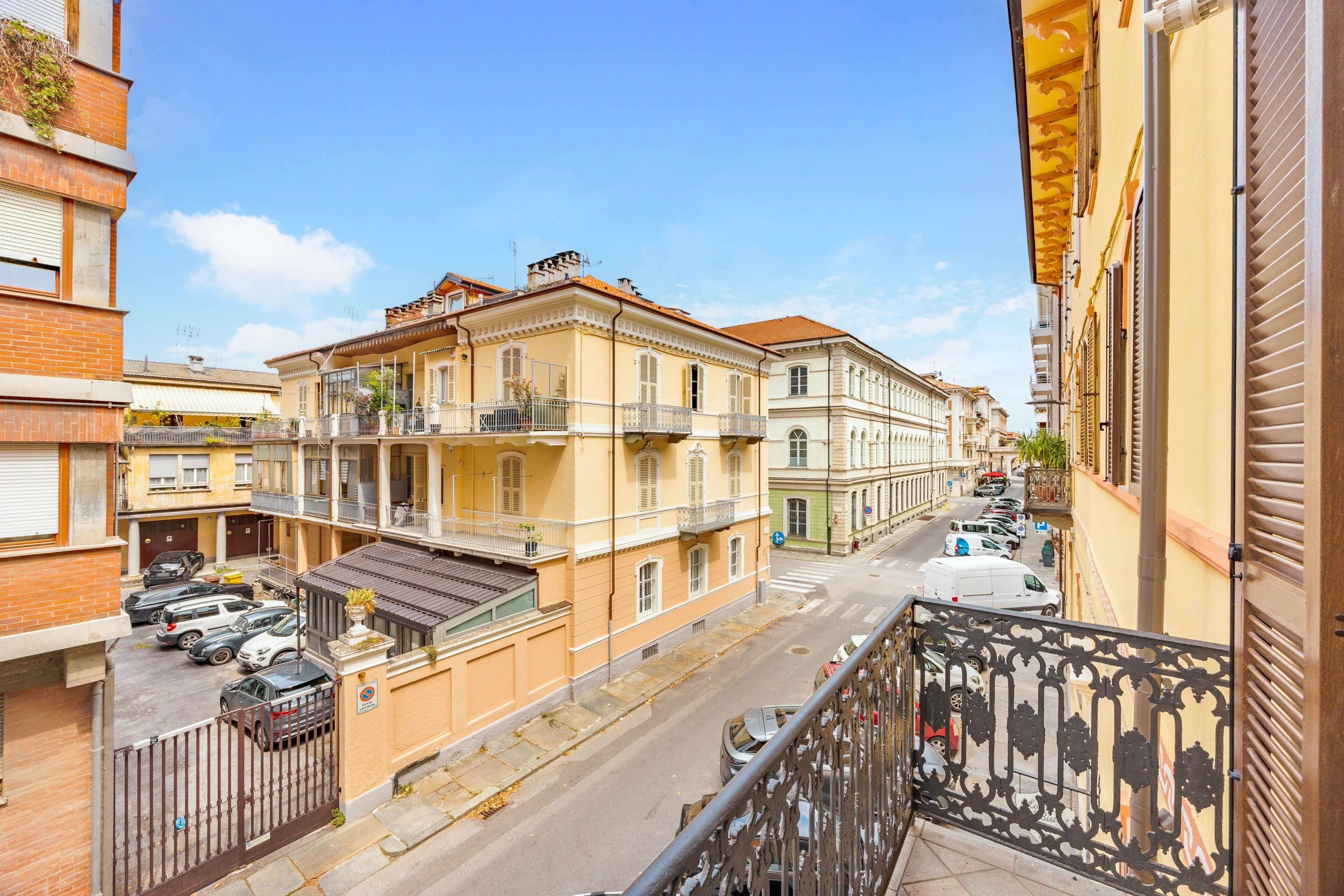 A street view with multi-story buildings, a clear sky, and parked cars.