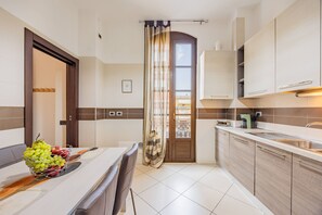 Una cocina moderna con comedor, que incluye una mesa con frutera, una isla de cocina y vistas a través de una puerta.