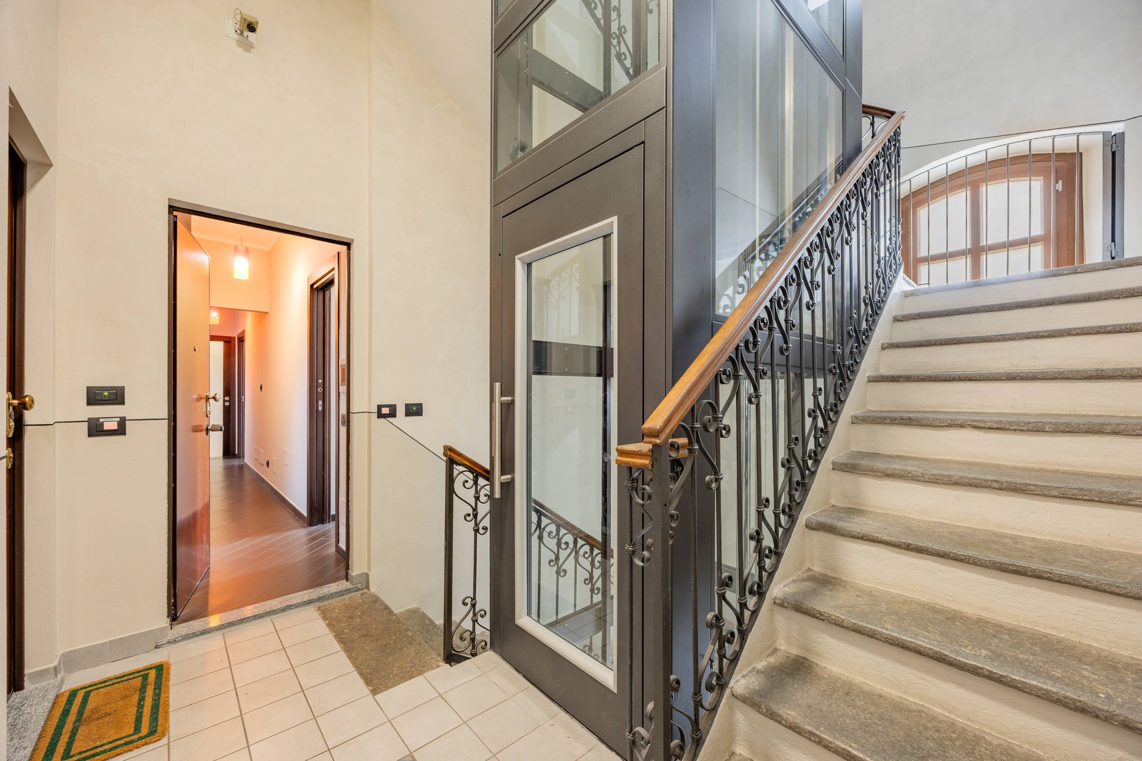Un escalier avec une rampe en métal et une porte dotée d’un panneau de verre.