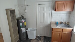 Una cocina con calentador de agua, lavadora, armarios de madera y un lavamanos.