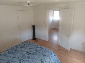 Un dormitorio con una cama, un calentador portátil y una puerta que da a otra habitación.