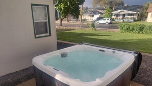 Un jacuzzi con revestimiento de madera, un taburete y una ventana con persianas.
