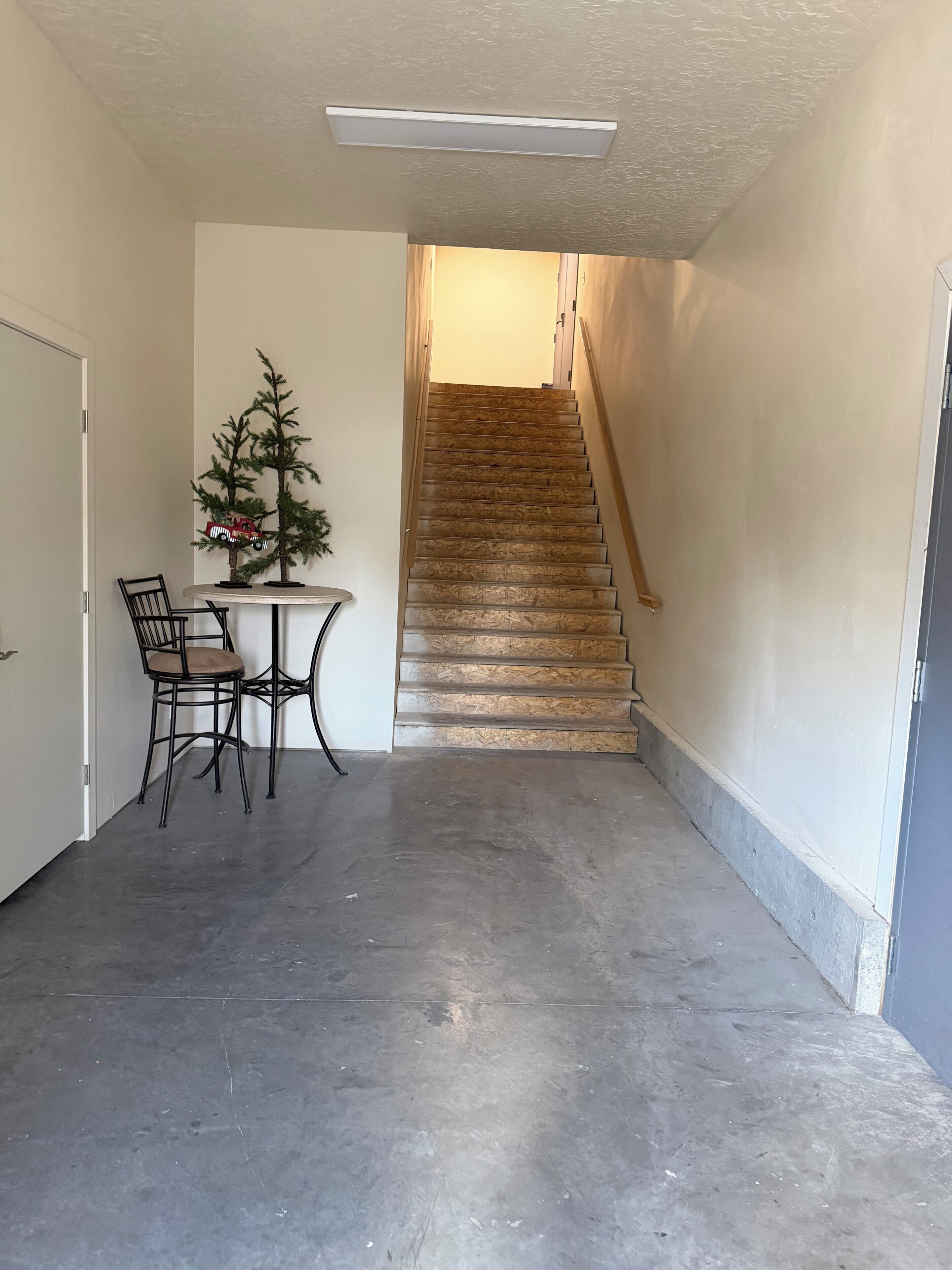 Un pasillo con una escalera, una pequeña mesa con sillas y un árbol de Navidad.