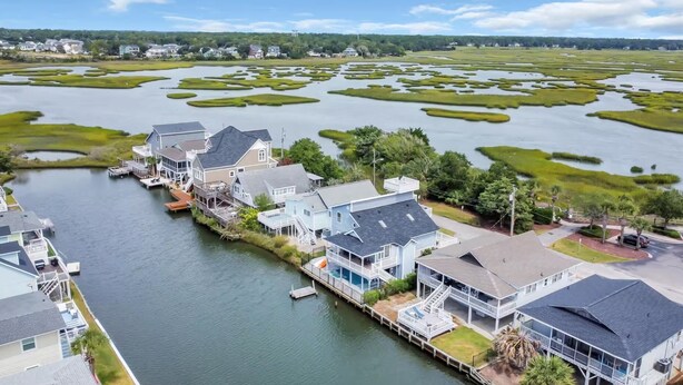 Une propriété située au bord de l’eau, comprenant plusieurs maisons, des quais et un paysage marécageux.