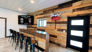 A bar area with a wooden wall, a scoreboard, and a neon sign. - Barndominium|Gameroom|Mini-Golf|Bar (Egg Harbor)
