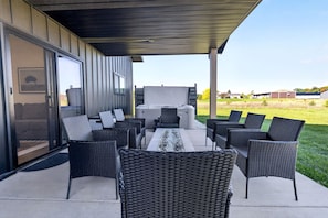 Een terras buiten met rieten meubilair, een vuurplaats en uitzicht op de omgeving.