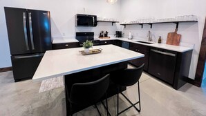 A modern kitchen with a central island, black appliances, and pendant lighting. - Barndominium|Gameroom|Mini-Golf|Bar (Egg Harbor)