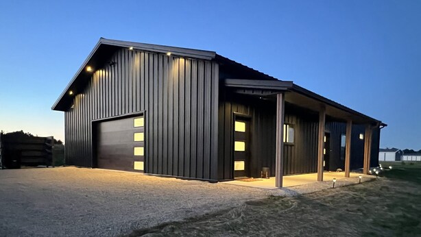 A modern building with a large garage door, a covered porch area, and a well-lit entrance. - Barndominium|Gameroom|Mini-Golf|Bar (Egg Harbor)