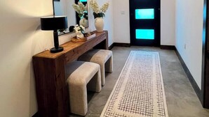 A hallway with a wooden console table, bench, mirror, and a patterned rug. - Barndominium|Gameroom|Mini-Golf|Bar (Egg Harbor)