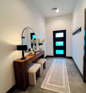 A hallway with a wooden console table, bench, mirror, and a patterned rug. - Barndominium|Gameroom|Mini-Golf|Bar (Egg Harbor)