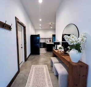 Una cocina moderna con una isla central, un comedor con banco y un pasillo que lleva a una puerta.