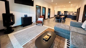 A modern living room with a fireplace, a flat-screen TV, a sofa, and a dining area. - Barndominium|Gameroom|Mini-Golf|Bar (Egg Harbor)