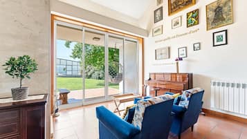 Una sala de estar con un piano, un sofá y una mesa de comedor.