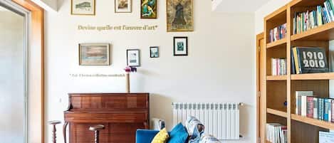 Una sala de estar con un sofá azul, un piano de madera y una estantería.