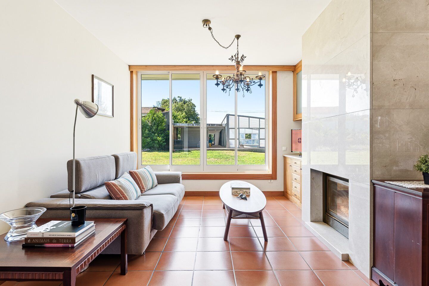 Una sala de estar con sofá, una mesa de centro, chimenea y un ventanal grande.