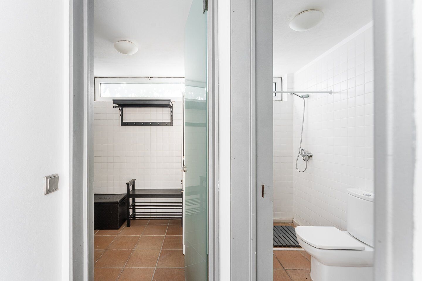 Une salle de bain moderne équipée d’une douche, de toilettes et d’un petit coin salon avec un banc et une table.